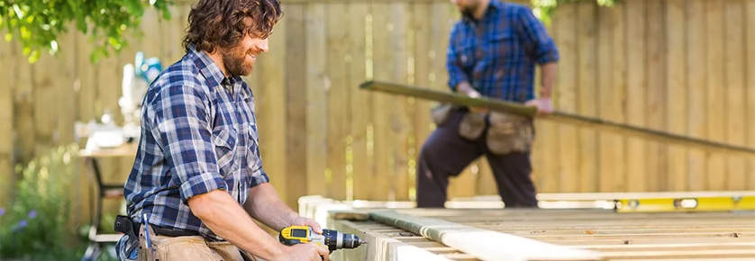 Person baut Holzterrasse mit Akkuschrauber